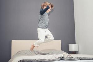 zorgeloos kind jumping Aan de bed. foto