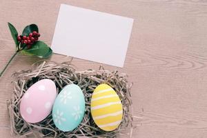 pastel en kleurrijk Pasen eieren in nest met blanco kaart Aan houten achtergrond, gelukkig Pasen vakantie concept foto