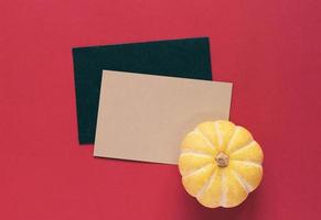 geel pompoen Aan blanco groet kaart met rood achtergrond, halloween of dankzegging concept foto