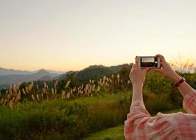 jong Aziatisch vrouw nemen een foto met haar telefoon in mooi berg visie