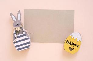 gelukkig Pasen concept met blanco kaart, houten konijn en kleurrijk Pasen eieren Aan geel achtergrond. top visie met kopiëren ruimte foto