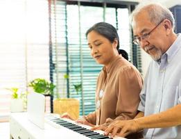 ouderen senior paar Speel piano muziek- samen. groep van twee Aziatisch slim volwassen persoon met pensioen gaan en krijgen pensioen fonds. grootouder uitdrukken gevoel gelukkig behandeling. concept toenemen oud samen, kopiëren ruimte foto