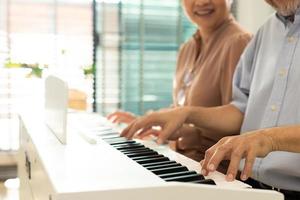 ouderen senior paar Speel piano muziek- samen. groep van twee Aziatisch slim volwassen persoon met pensioen gaan en krijgen pensioen fonds. grootouder uitdrukken gevoel gelukkig behandeling. concept toenemen oud samen, kopiëren ruimte foto