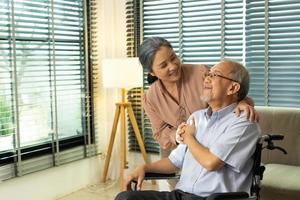 senior ouderen paar houden handen samen na pensioen, man vrouw persoon nemen zorg elk andere in romantisch tijd met glimlach gelukkig genieten. Aziatisch grootouder zitten Aan wiel stoel op zoek, kopiëren ruimte foto