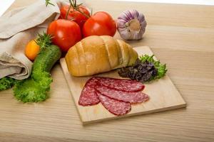 salami Aan houten bord en houten achtergrond foto