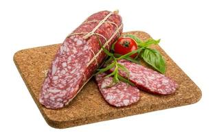 salami Aan houten bord en wit achtergrond foto