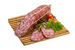 salami Aan houten bord en wit achtergrond foto