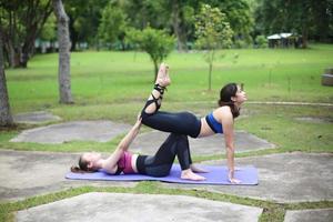 twee jong aantrekkelijk vrouw aan het doen uitrekken yoga oefening in de park. foto