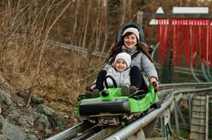 moeder met dochter rijden elektrisch slee Aan rails. foto