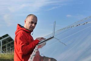 ingenieur gebruik makend van laptop Bij zonne- panelen fabriek veld- foto