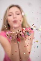vrouw blazen confetti in de lucht foto