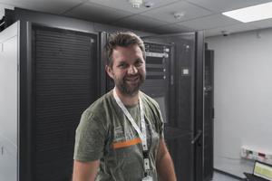 portret van mannetje technicus of netwerk beheerder staand dapper net zo een held met armen gekruiste in gegevens centrum server kamer. foto