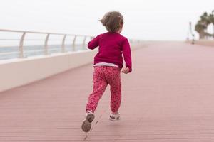 schattig weinig meisje Aan de promenade door de zee foto