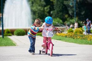 jongen en meisje in park aan het leren naar rijden een fiets foto