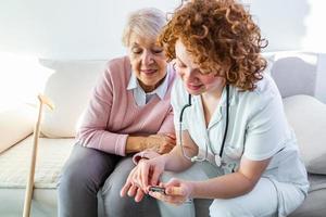 verpleegster meten bloed suiker van senior vrouw Bij huis. jong verpleegster meten bloed suiker van ouderen vrouw Bij huis. dokter controle ouderen vrouw bloed suiker - diabetes en glikemie concept foto