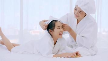 moeder met weinig dochter in badjassen aan het doen schoonheid behandeling samen in slaapkamer. foto