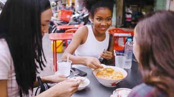 een groep van multi-etnisch vrouw vrienden genieten van straat voedsel Aan yaowarat weg of Chinatown in Bangkok, Thailand. foto