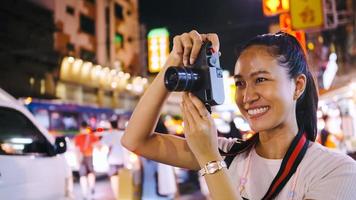 een Aziatisch vrouw toerist geniet nemen foto's van de nacht visie van yaowarat weg of Chinatown in Bangkok, Thailand. foto