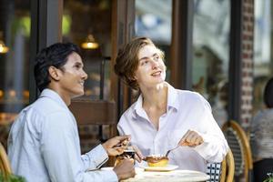 Kaukasisch paar hebben een datum Bij Europese stijl cafe bistro genieten van ochtend- uitstraling in de omgeving van de stad plein met zoet gebakje en een kop van koffie foto