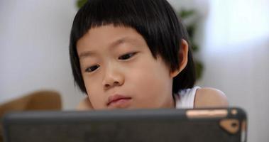schattig weinig jongen gebruik makend van tablet computer Bij huis. foto