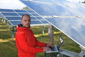 ingenieur gebruik makend van laptop Bij zonne- panelen fabriek veld- foto
