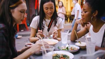 een groep van multi-etnisch vrouw vrienden genieten van straat voedsel Aan yaowarat weg of Chinatown in Bangkok, Thailand. foto