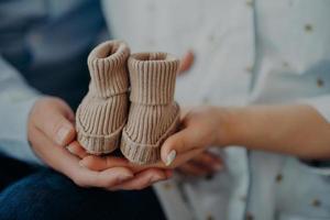 bijgesneden schot van toekomst ouders anticiperen voor kind houden baby laarzen tonen klein schoenen voor komt eraan baby. ouderschap zwangerschap geboorte liefde en familie concept. foto