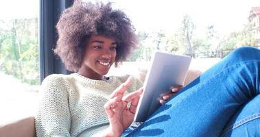 Afrikaanse Amerikaans vrouw Bij huis gebruik makend van digitaal tablet foto