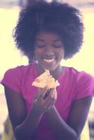 vrouw met afro kapsel aan het eten smakelijk pizza plak foto