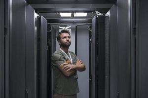 portret van mannetje technicus of netwerk beheerder staand dapper net zo een held met armen gekruiste in gegevens centrum server kamer. foto