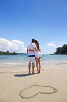 romantisch paar in liefde hebben pret Aan de strand met hart tekening Aan zand foto