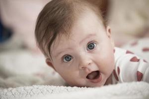 schattig weinig baby spelen met handen en glimlachen foto