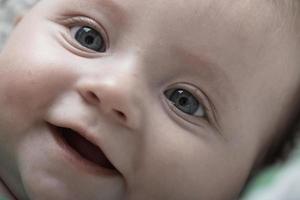 schattig weinig baby spelen met handen en glimlachen foto