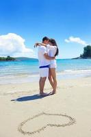 romantisch paar in liefde hebben pret Aan de strand met hart tekening Aan zand foto