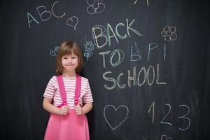 school- meisje kind met rugzak schrijven schoolbord foto