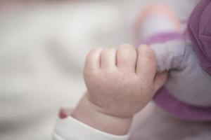 schattig weinig baby spelen met handen en glimlachen foto