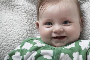 schattig weinig baby spelen met handen en glimlachen foto