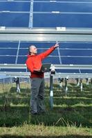 ingenieur gebruik makend van laptop Bij zonne- panelen fabriek veld- foto