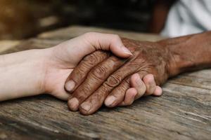 handen van de oud Mens en een vrouw hand- Aan de hout tafel foto