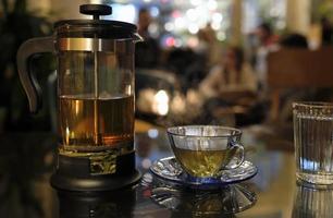 vers kruiden thee in een transparant thee druk op in een knus cafe in de avond foto