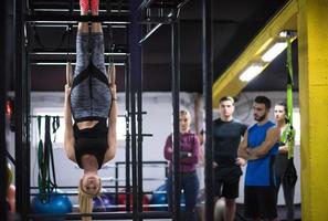 vrouw werken uit met persoonlijk trainer Aan gymnastiek- ringen foto