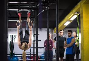 vrouw werken uit met persoonlijk trainer Aan gymnastiek- ringen foto