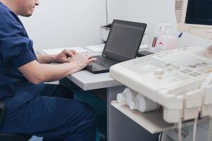 orthopedist dokter onderzoeken röntgenstraal afbeelding Bij bureau in kliniek Aan laptop computer foto