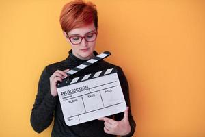 roodharige vrouw Holding film klepel Aan geel achtergrond foto