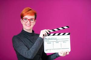 roodharige vrouw Holding film klepel Aan roze achtergrond foto