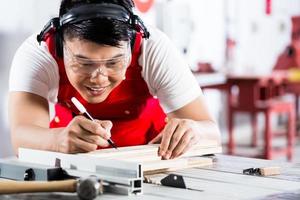 Aziatische Chinese timmerman snijden hout met zaag