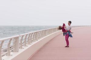 moeder en schattig weinig meisje Aan de promenade door de zee foto