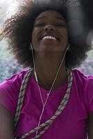 portret van jong afro Amerikaans vrouw in Sportschool terwijl luisteren muziek- foto