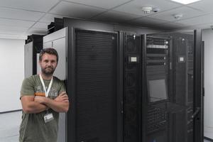 portret van mannetje technicus of netwerk beheerder staand dapper net zo een held met armen gekruiste in gegevens centrum server kamer. foto