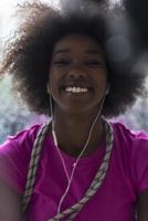 portret van jong afro Amerikaans vrouw in Sportschool terwijl luisteren muziek- foto